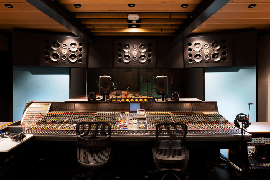 Music control room Large mixing desk with monitors and speakers above, behind window facing into auditorium